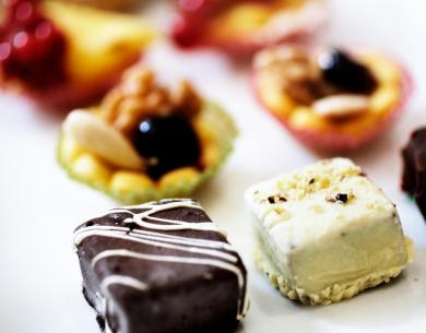 Dolci assortiti su un piatto bianco, decorati con cioccolato e frutta.