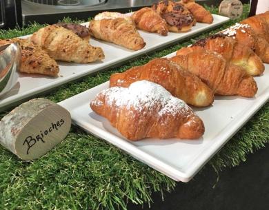 Vassoi di brioches assortite su un tavolo decorato con erba finta.