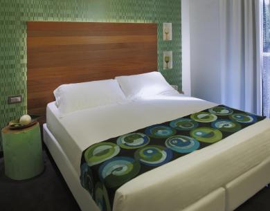 Camera moderna con letto matrimoniale e decorazioni verdi.