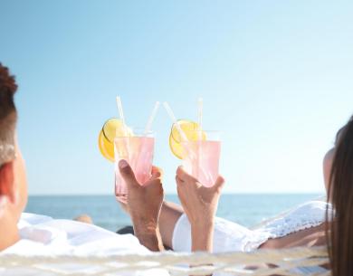 Coppia rilassata sulla spiaggia con cocktail rosa.