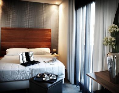 Chambre moderne avec lit, ordinateur portable et plateau café.