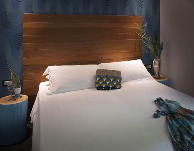 Modernes Schlafzimmer mit Holzkopfteil und blauen Dekorationen.