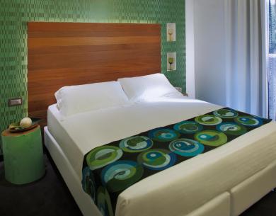 Modernes Zimmer mit Doppelbett und grüner Dekoration.
