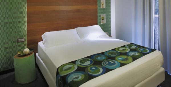 Camera moderna con letto matrimoniale e decorazioni verdi.
