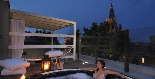 Femme dans jacuzzi sur terrasse avec bougies et vue nocturne.