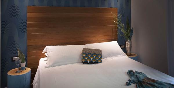 Modernes Schlafzimmer mit Holzkopfteil und blauen Dekorationen.