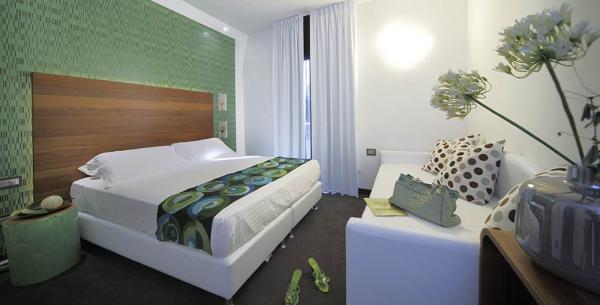 Chambre moderne avec lit double, canapé et décorations vertes.