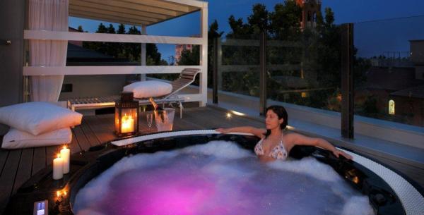 Femme se relaxant dans un jacuzzi sur une terrasse au coucher du soleil.