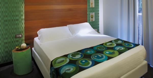 Modernes Zimmer mit Doppelbett und grüner Dekoration.